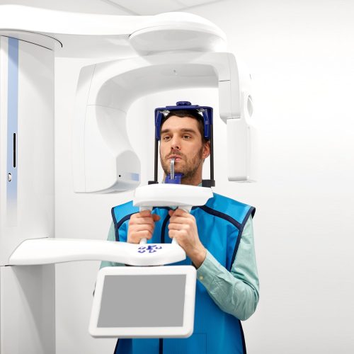 medicine, dentistry and healthcare concept - male patient having panoramic x-ray scanning procedure at dental clinic